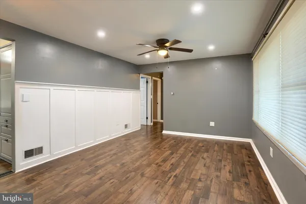 an empty room with wooden floor chandelier fan and windows
