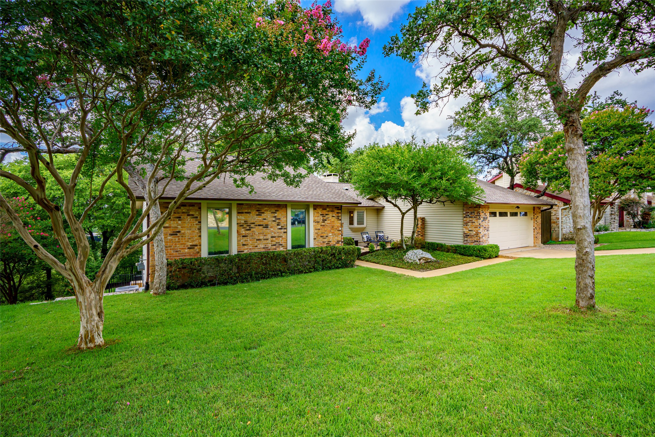 Ranch-style house with a front yard, brick siding, a garage, and concrete driveway
