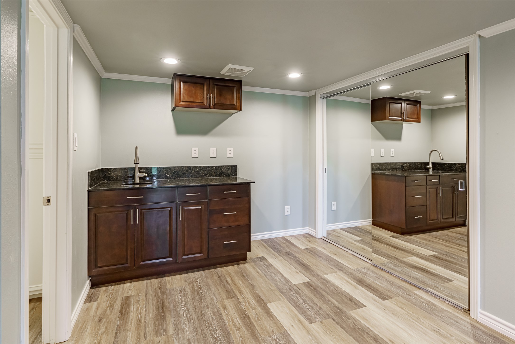 8810 Mountain Path Circle Austin, TX 78759 - Photo 22 of 37 Indoor wet bar featuring dark stone counters, recessed lighting, crown molding, light wood-style floors, and dark brown cabinets