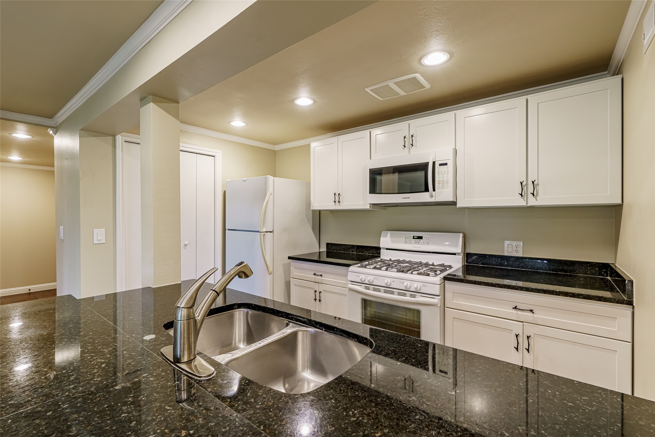 8810 Mountain Path Circle Austin, TX 78759 - Photo 25 of 37 Kitchen with white appliances, white cabinets, ornamental molding, recessed lighting, and dark stone countertops