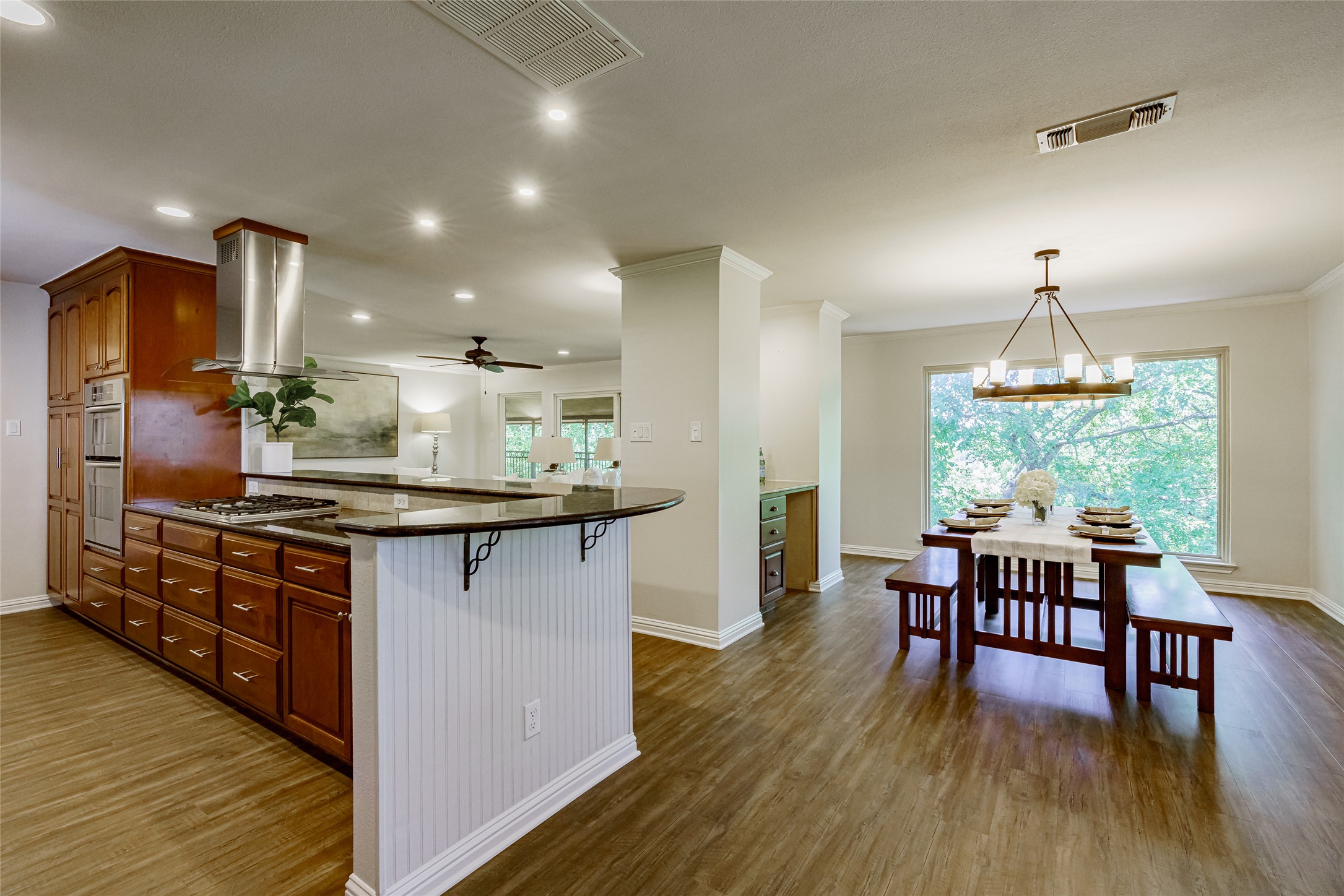 8810 Mountain Path Circle Austin, TX 78759 - Photo 4 of 37 Kitchen featuring dark wood finished floors, island range hood, dark stone countertops, ceiling fan, and ornamental molding