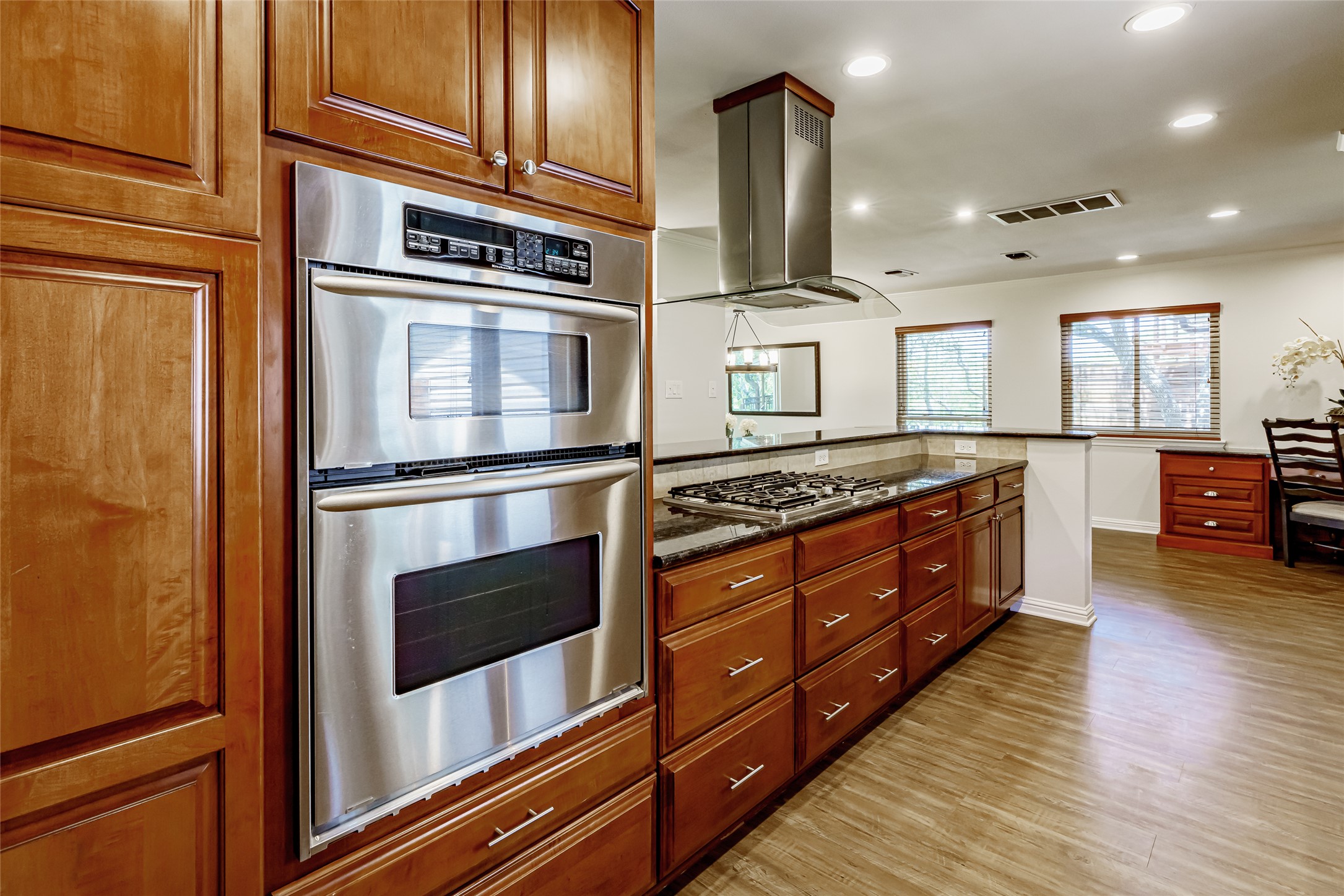 8810 Mountain Path Circle Austin, TX 78759 - Photo 6 of 37 Kitchen featuring recessed lighting, appliances with stainless steel finishes, dark stone countertops, island exhaust hood, and dark wood-style flooring