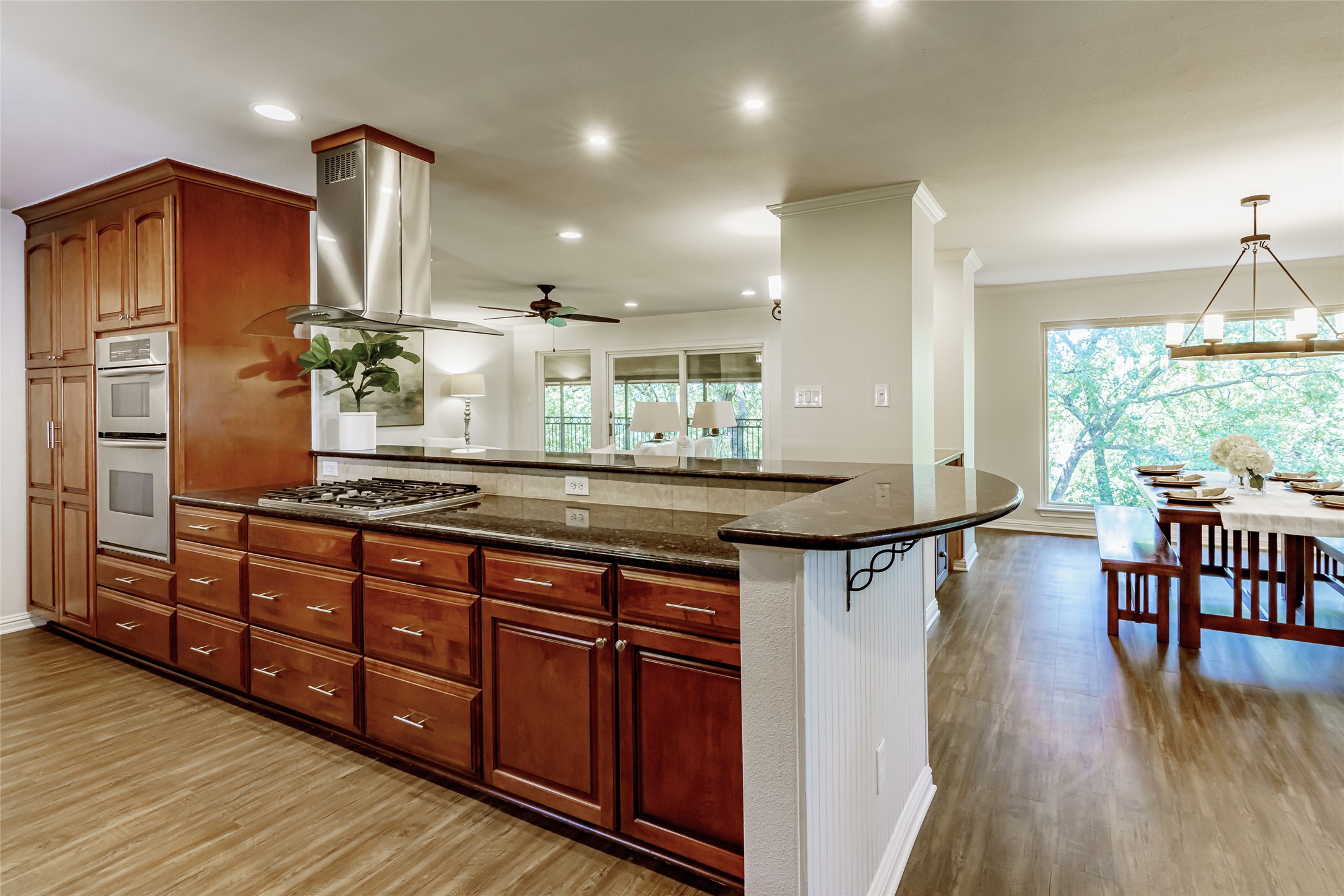 8810 Mountain Path Circle Austin, TX 78759 - Photo 7 of 37 Kitchen featuring dark stone counters, island range hood, double oven, light wood-style floors, and ceiling fan