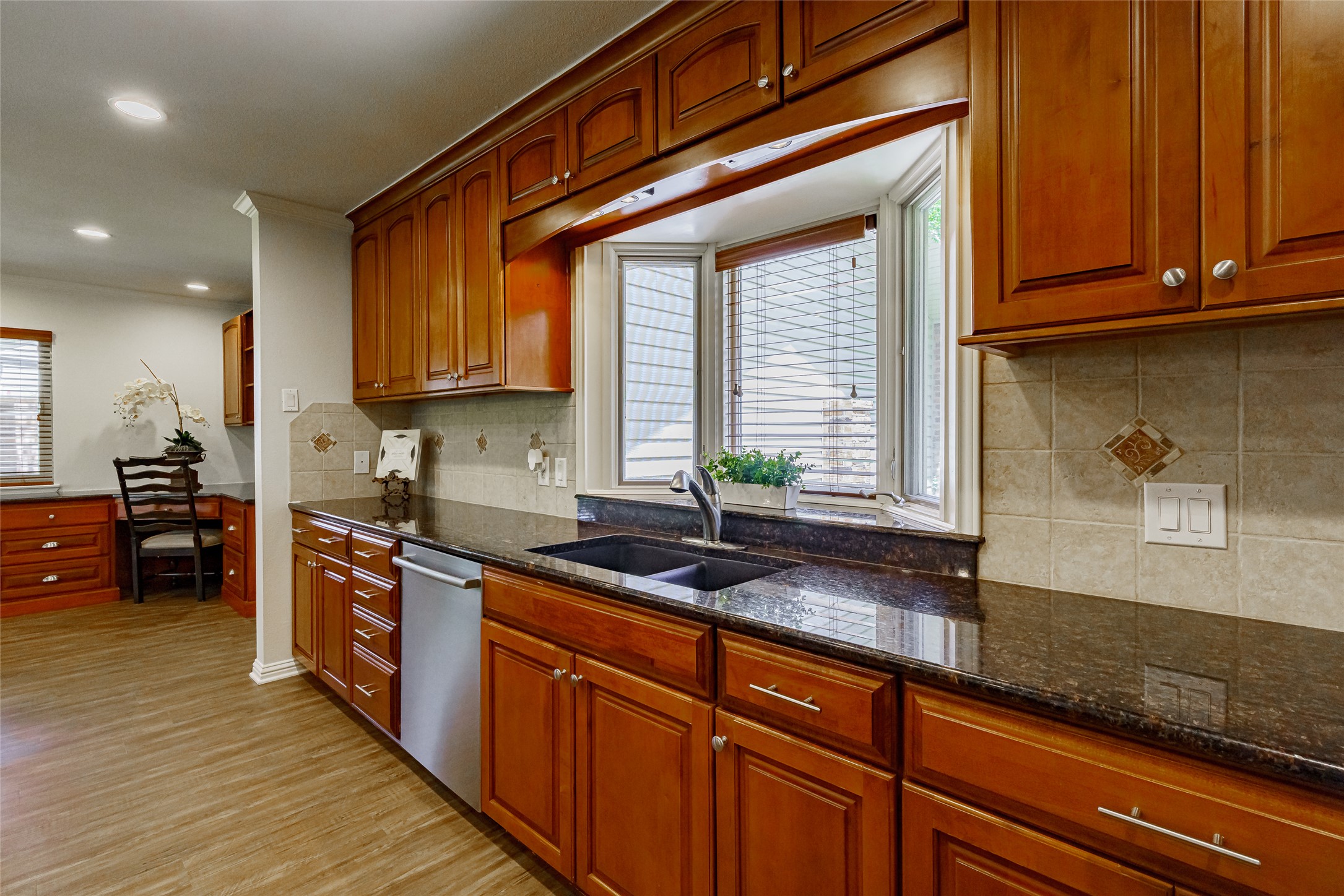 8810 Mountain Path Circle Austin, TX 78759 - Photo 9 of 37 Kitchen featuring dark stone countertops, dishwasher, light wood-type flooring, recessed lighting, and backsplash