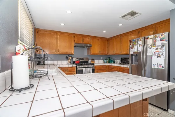 a kitchen with stainless steel appliances kitchen island granite countertop a refrigerator a stove a sink dishwasher and white cabinets with wooden floor