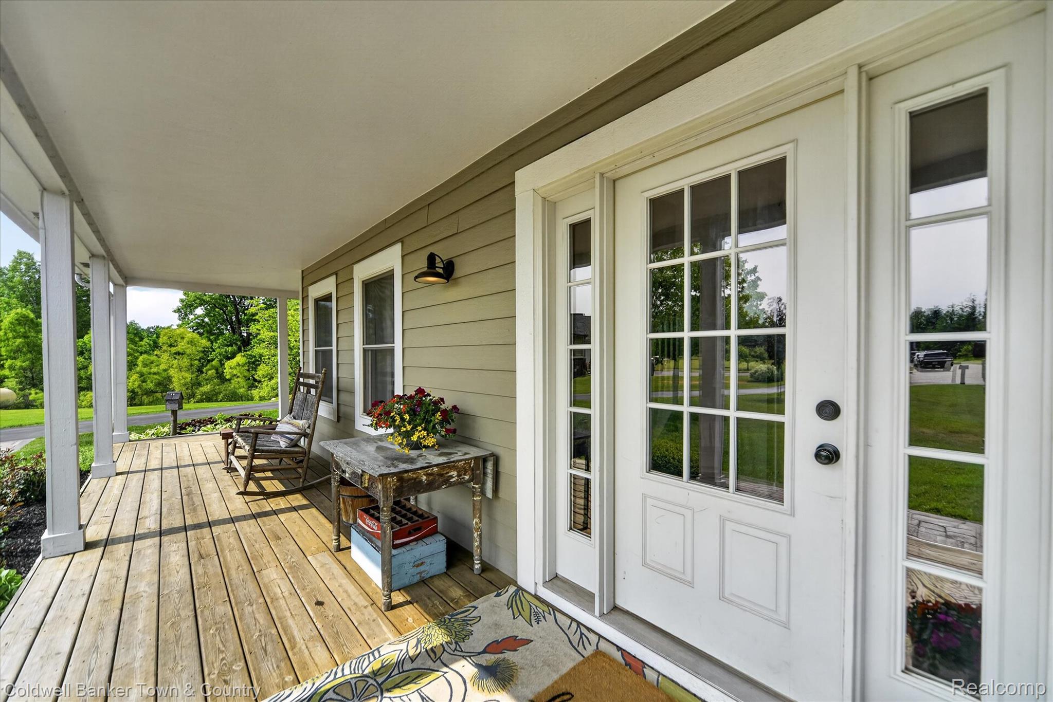 918 Gray Fox Court Howell, MI 48843 - Photo 6 of 84 Inviting front porch featuring a wood-finish deck, white columns, and a light-colored siding exterior