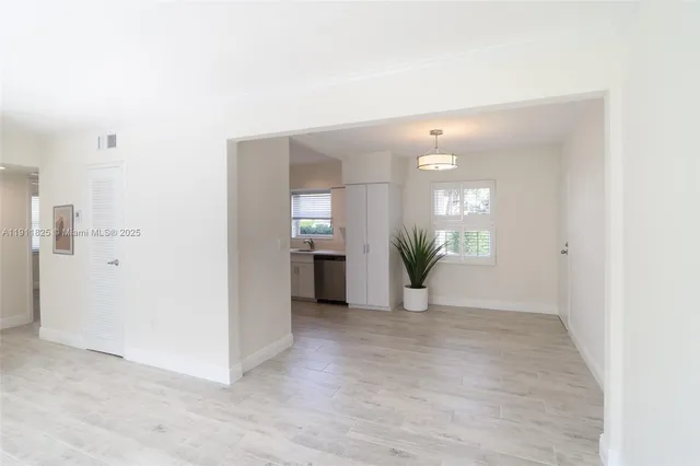 an empty room with kitchen and windows