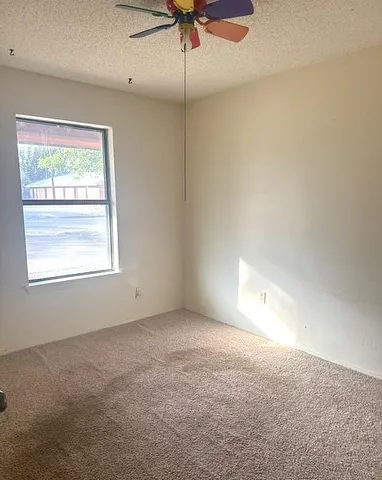 an empty room with a window and a fan