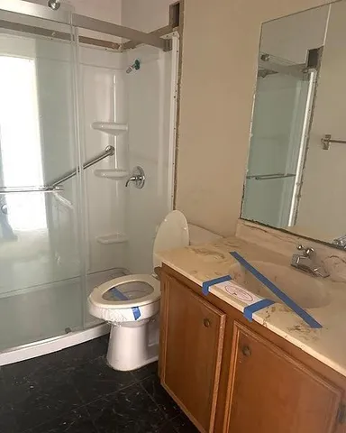 a bathroom with a granite countertop sink toilet and shower
