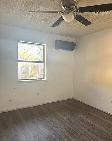an empty room with wooden floor fan and windows