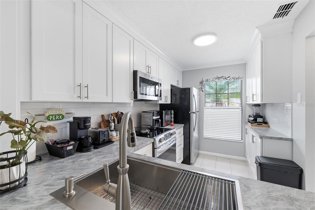 1804 Rising Sun Drive, Unit 1804 Holiday, FL 34690 - Photo 11 of 31 a kitchen with stainless steel appliances granite countertop a refrigerator sink and stove top oven