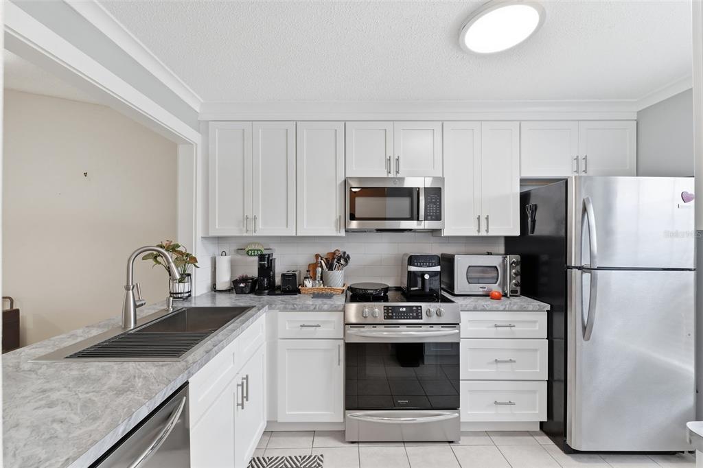 1804 Rising Sun Drive, Unit 1804 Holiday, FL 34690 - Photo 13 of 31 a kitchen with refrigerator a stove a sink and white cabinets