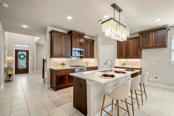 a kitchen with stainless steel appliances granite countertop a stove top oven a sink dishwasher a dining table and chairs with wooden floor