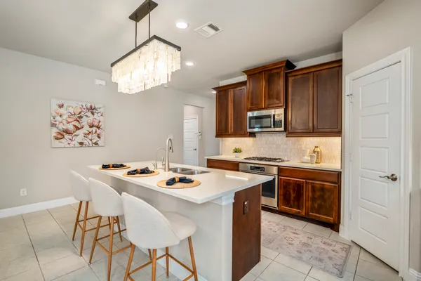 a kitchen with stainless steel appliances granite countertop a stove a sink dishwasher and a refrigerator with wooden cabinets