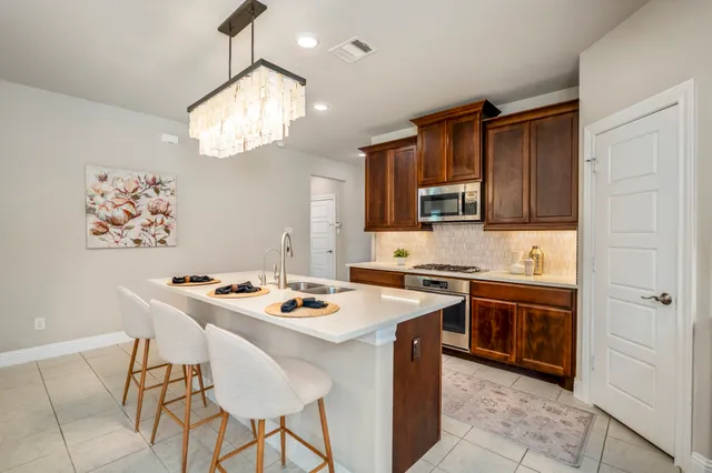 a kitchen with stainless steel appliances granite countertop a stove a sink dishwasher and a refrigerator with wooden cabinets