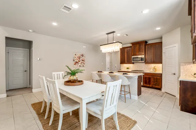 a dining room with stainless steel appliances kitchen island granite countertop a dining table chairs and a refrigerator