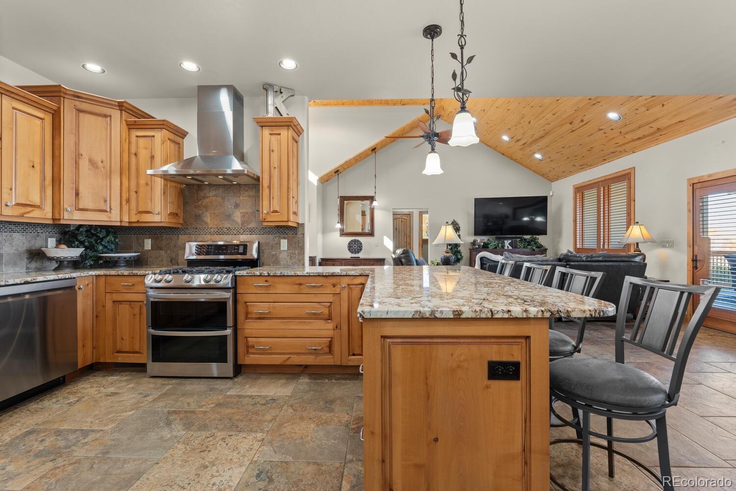 60075 Oak Grove Road Montrose, CO 81403 - Photo 14 of 50 a kitchen with kitchen island granite countertop a stove and a view of living room