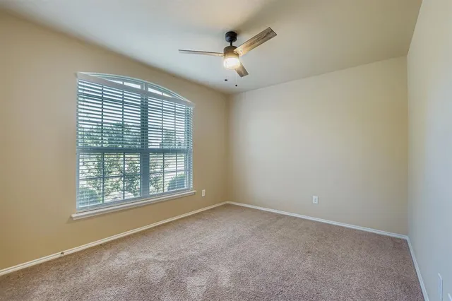 an empty room with windows and ceiling fan