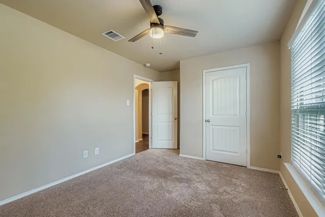 an empty room with a window and a ceiling fan