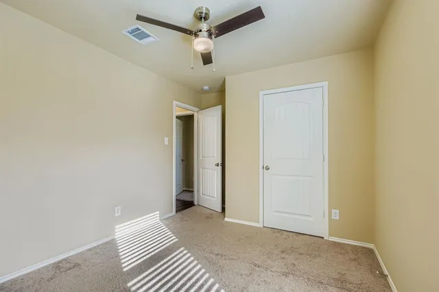 an empty room with closet and a chandelier fan