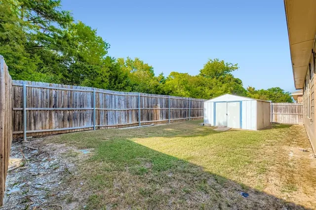 a view of a backyard with a small cabin and wooden fence