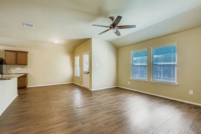 a view of an empty room with window and wooden floor