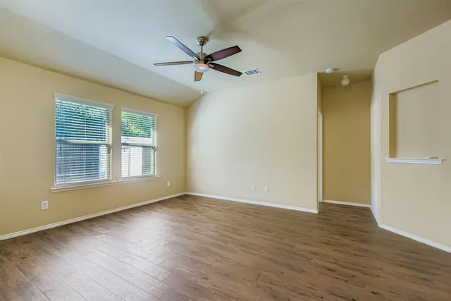 a view of empty room with wooden floor and fan