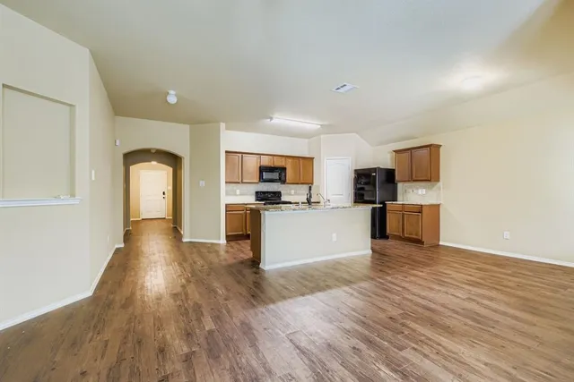 a view of kitchen with microwave a refrigerator and wooden floor