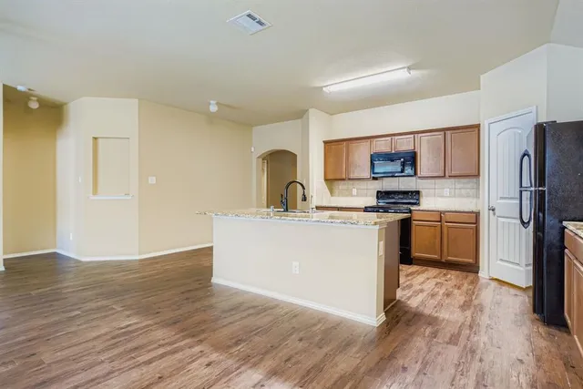 a kitchen with a refrigerator a stove top oven a sink and dishwasher with wooden floor