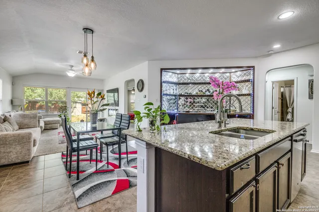 a kitchen with granite countertop a sink and chairs