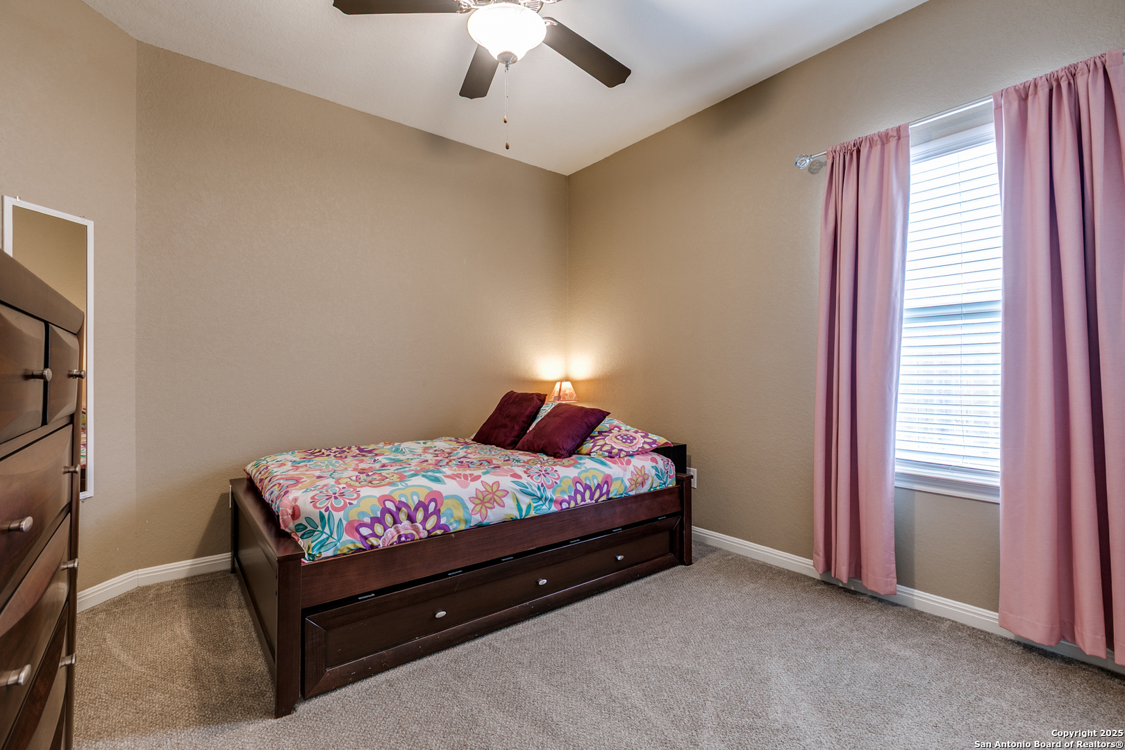 305 Iron Gate Pleasanton, TX 78064 - Photo 22 of 25 a bed sitting in a bedroom next to a window and a chandelier