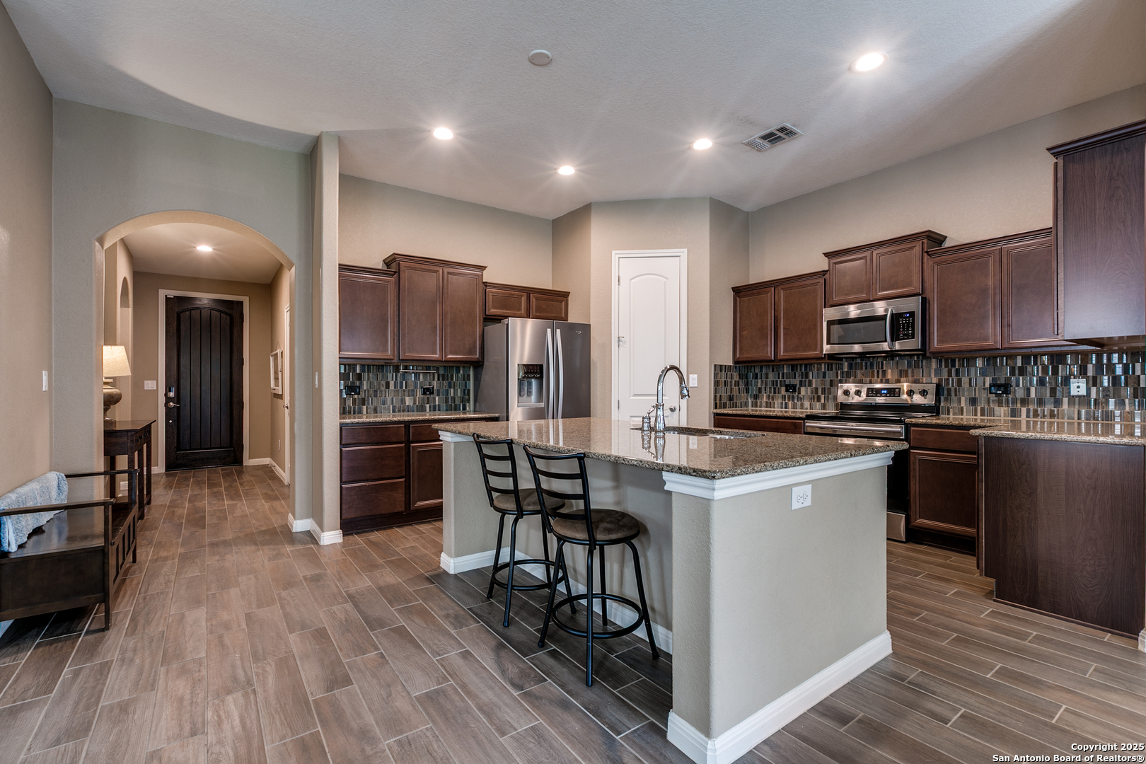 305 Iron Gate Pleasanton, TX 78064 - Photo 6 of 25 a kitchen with kitchen island granite countertop wooden floors appliances and cabinets