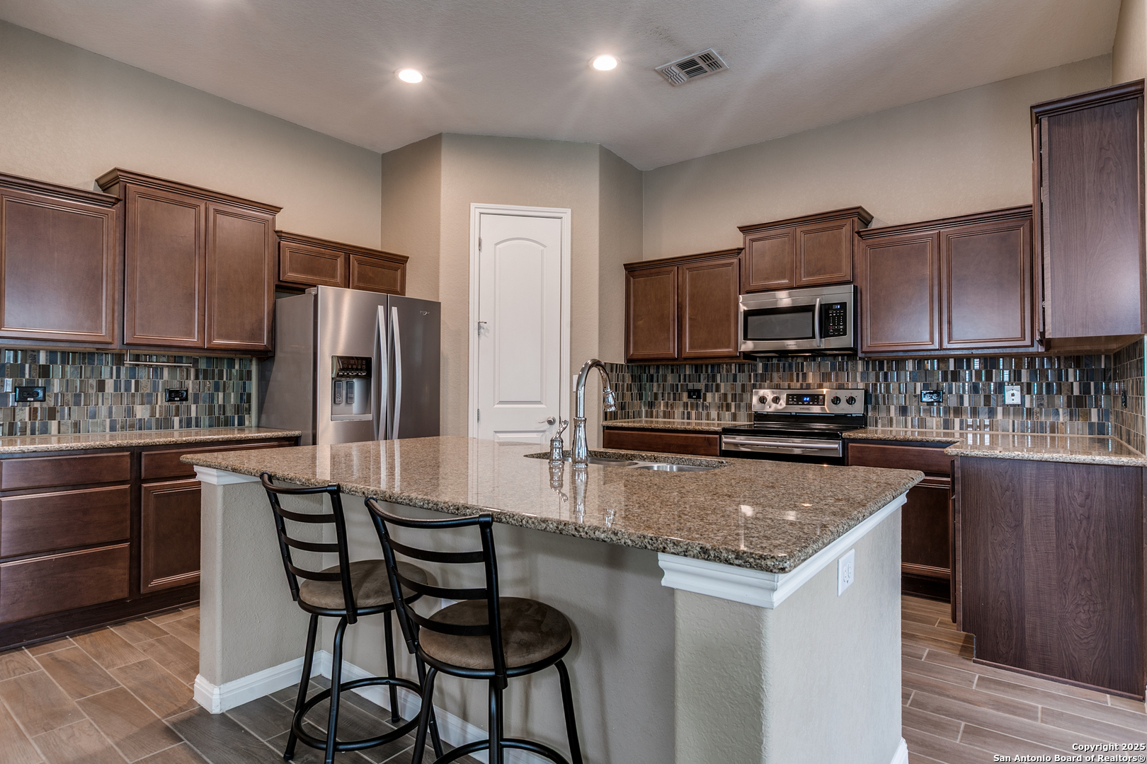 305 Iron Gate Pleasanton, TX 78064 - Photo 9 of 25 a kitchen with stainless steel appliances granite countertop a stove a sink a refrigerator a microwave and cabinets