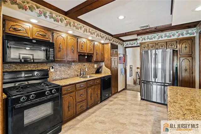 a kitchen with stainless steel appliances granite countertop a stove a sink and a refrigerator