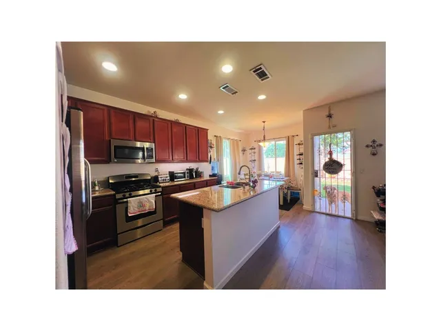 a living room with stainless steel appliances kitchen island granite countertop a refrigerator a sink dishwasher a oven with wooden cabinets