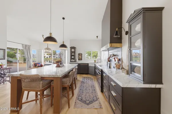 a dining hall with stainless steel appliances kitchen island granite countertop a table chairs and a large window