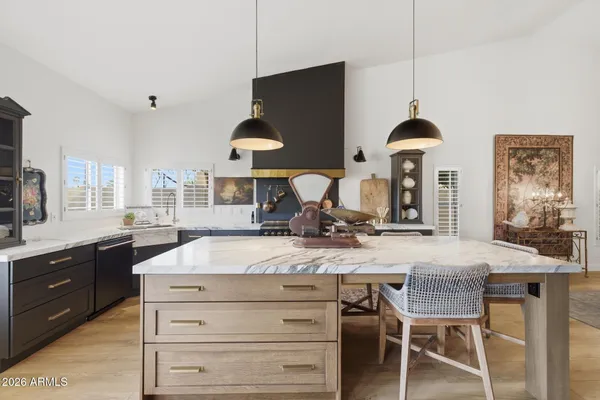 a kitchen with kitchen island granite countertop a table chairs sink and cabinets