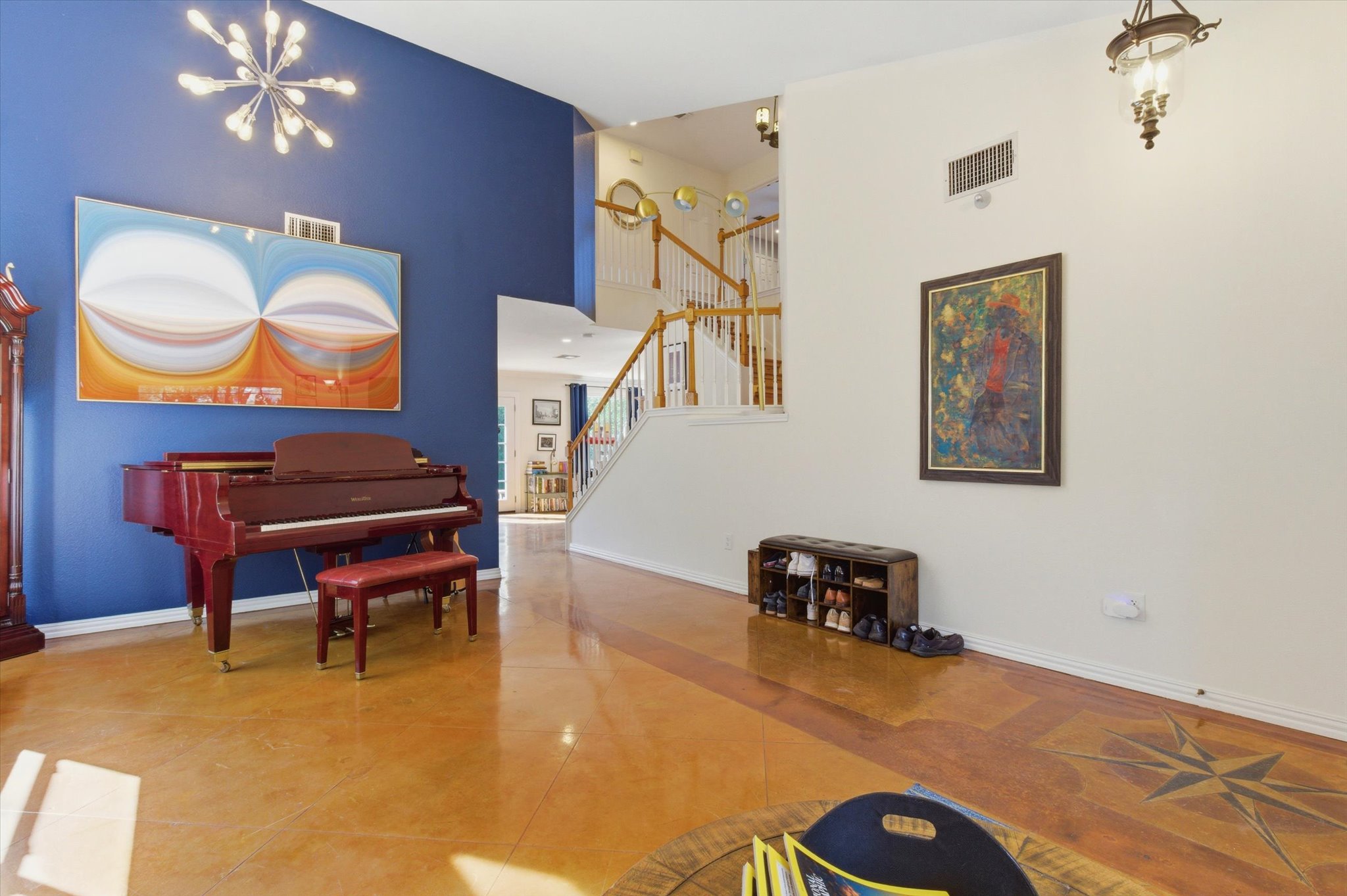8920 West Hove Loop Austin, TX 78749 - Photo 4 of 39 Vaulted ceiling entry featuring a contemporary chandelier, grand staircase with wood railing, warm-toned flooring with inlaid compass design, and a secondary hanging light fixture