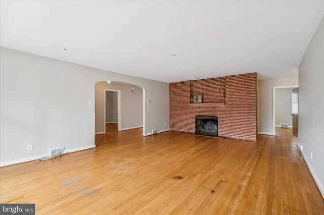 a view of empty room with wooden floor and fireplace