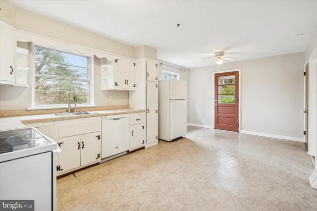 a large white kitchen with a stove a sink dishwasher and a refrigerator