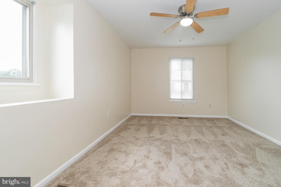 76 King Henry Circle, Unit 76B Baltimore, MD 21237 - Photo 25 of 29 an empty room with a window and a ceiling fan