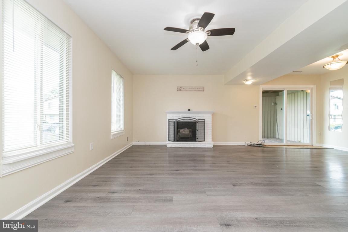 76 King Henry Circle, Unit 76B Baltimore, MD 21237 - Photo 4 of 29 an empty room with wooden floor fireplace and windows
