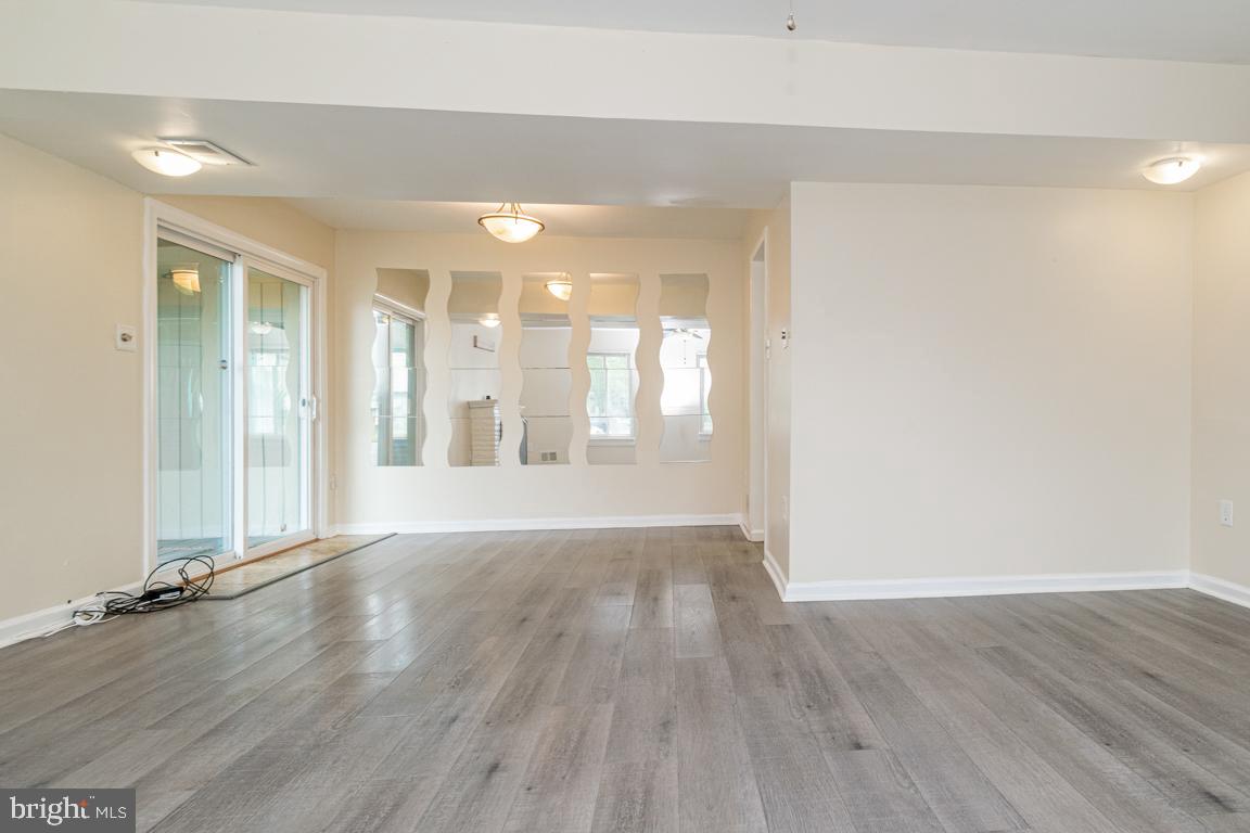 76 King Henry Circle, Unit 76B Baltimore, MD 21237 - Photo 5 of 29 an empty room with wooden floor and windows