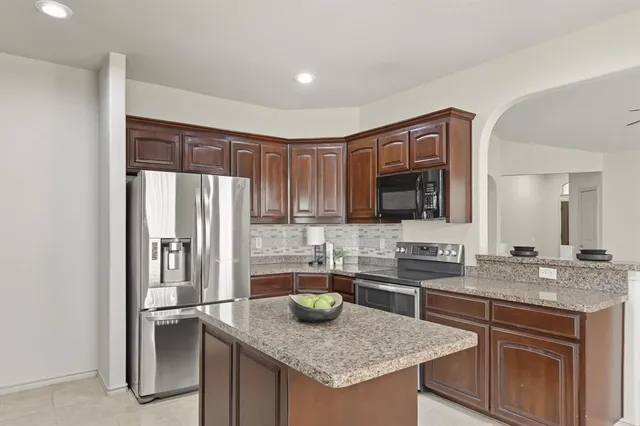 a kitchen with stainless steel appliances granite countertop a sink and a refrigerator