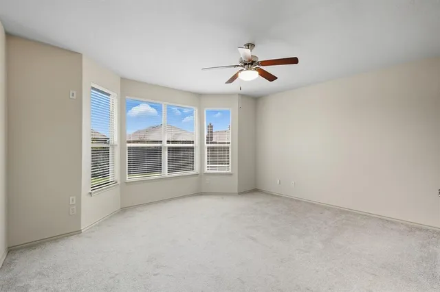 an empty room with windows and fan