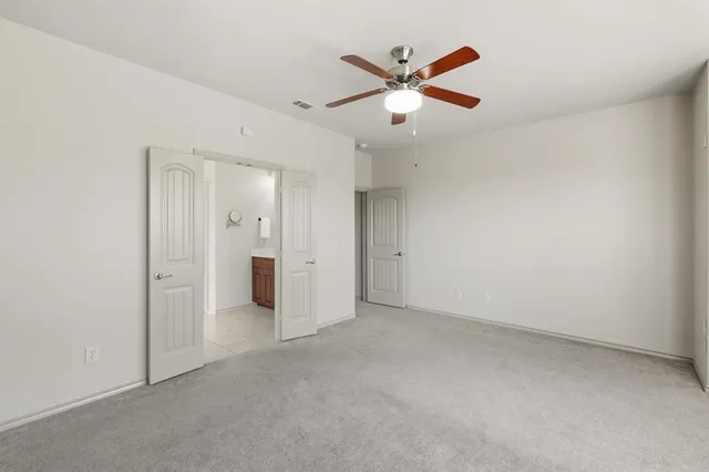 an empty room with closet and a chandelier fan