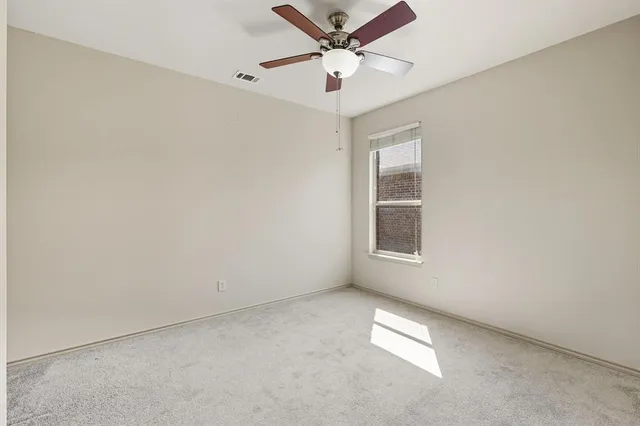 an empty room with a window and a fan