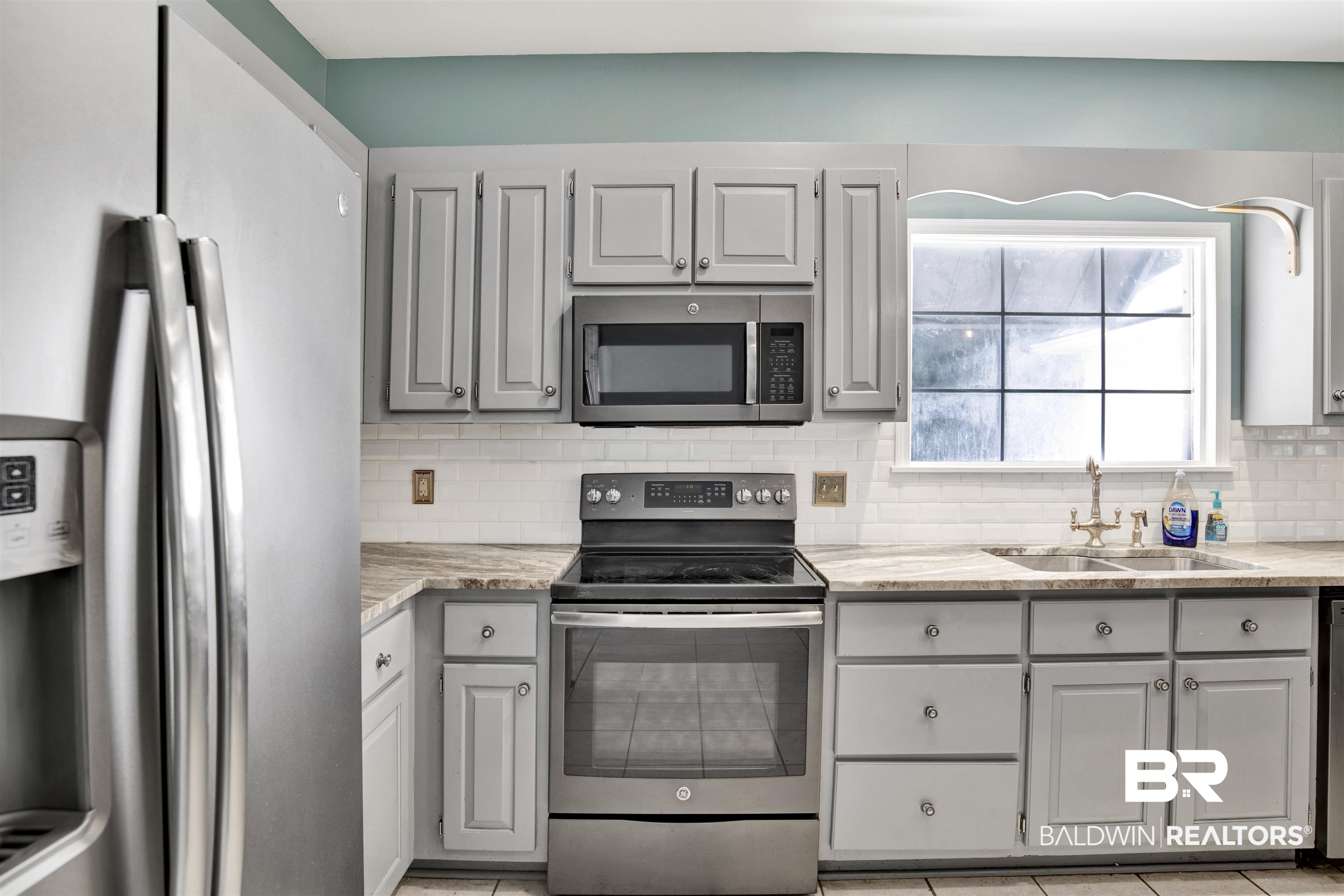 11835 Island Drive Foley, AL 36535 - Photo 28 of 53 Kitchen featuring appliances with stainless steel finishes, gray cabinets, light tile patterned floors, and decorative backsplash