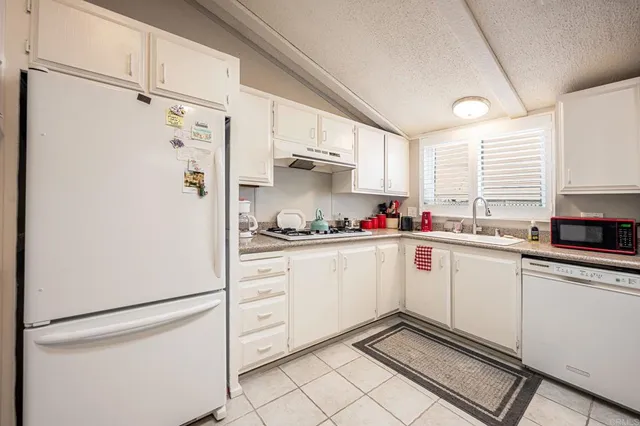 a kitchen with granite countertop white cabinets and white appliances