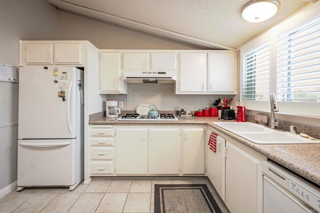 4650 Dulin Road, Unit 111 Fallbrook, CA 92003 - Photo 19 of 35 a kitchen with stainless steel appliances granite countertop a refrigerator sink and white cabinets